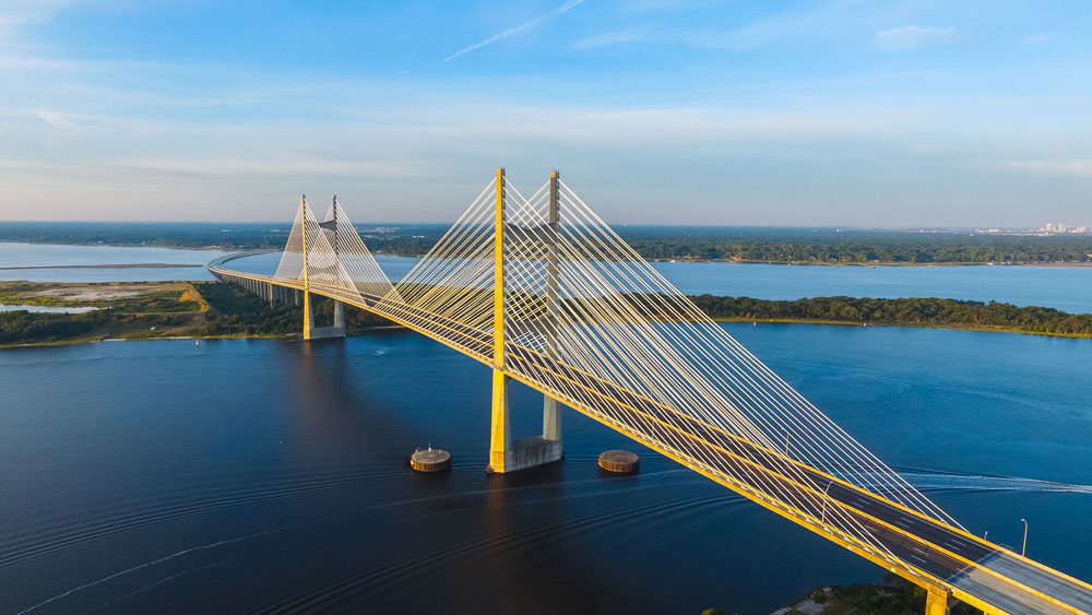 Pont suspendu jaune passant au dessus d'une étendue d'eau
